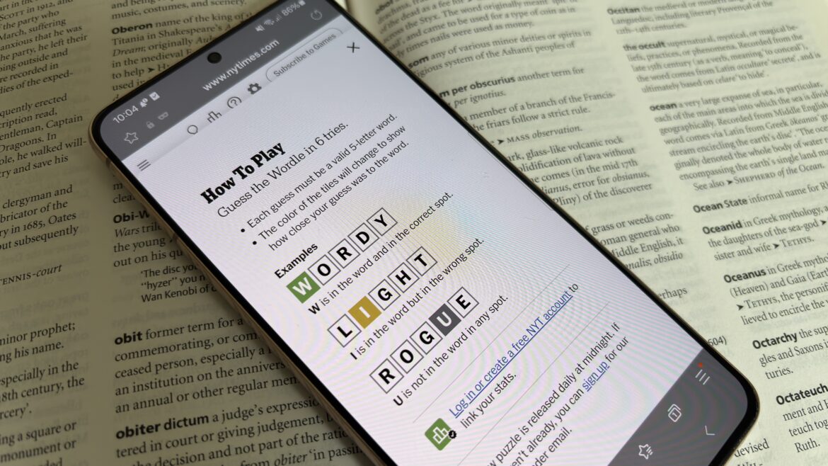 A phone playing Wordle, laid on top of a dictionary