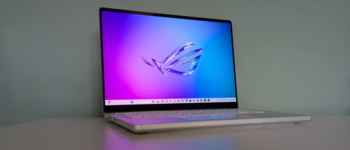 Three-quarter view of Asus ROG Zephyrus G14 (2025) open on desk with green wall in background