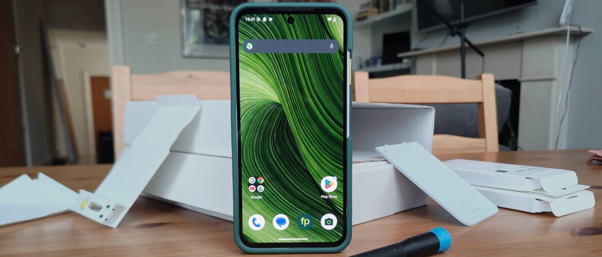 The Fairphone 6 standing before various boxes.