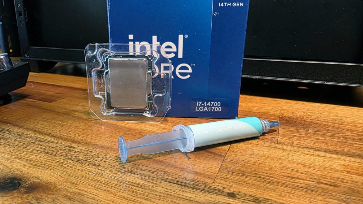 An Intel Core i7-14700 CPU box, along with a cleaned-off version of the Core i5-13500 that was inside, next to a syringe of thermal paste
