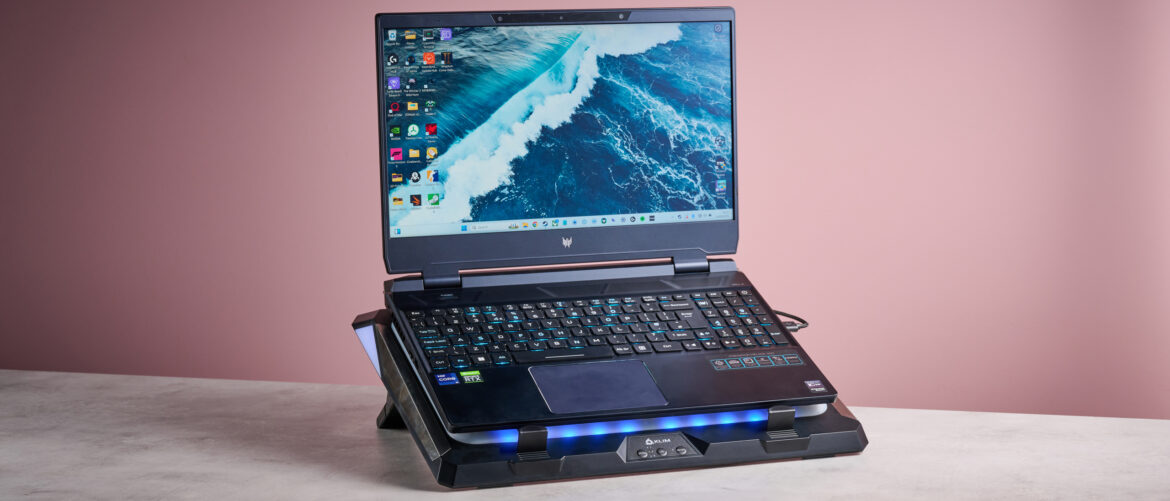 Klim Mistral review: this comfortable laptop cooling pad is almost An Acer Predator Helios 300 laptop sat on top of the Klim Mistral laptop cooling pad in front of a pink background.