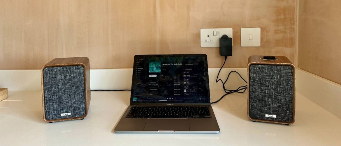 Ruark MR1 Mk3 powered speakers either side of a laptop, on a white surface